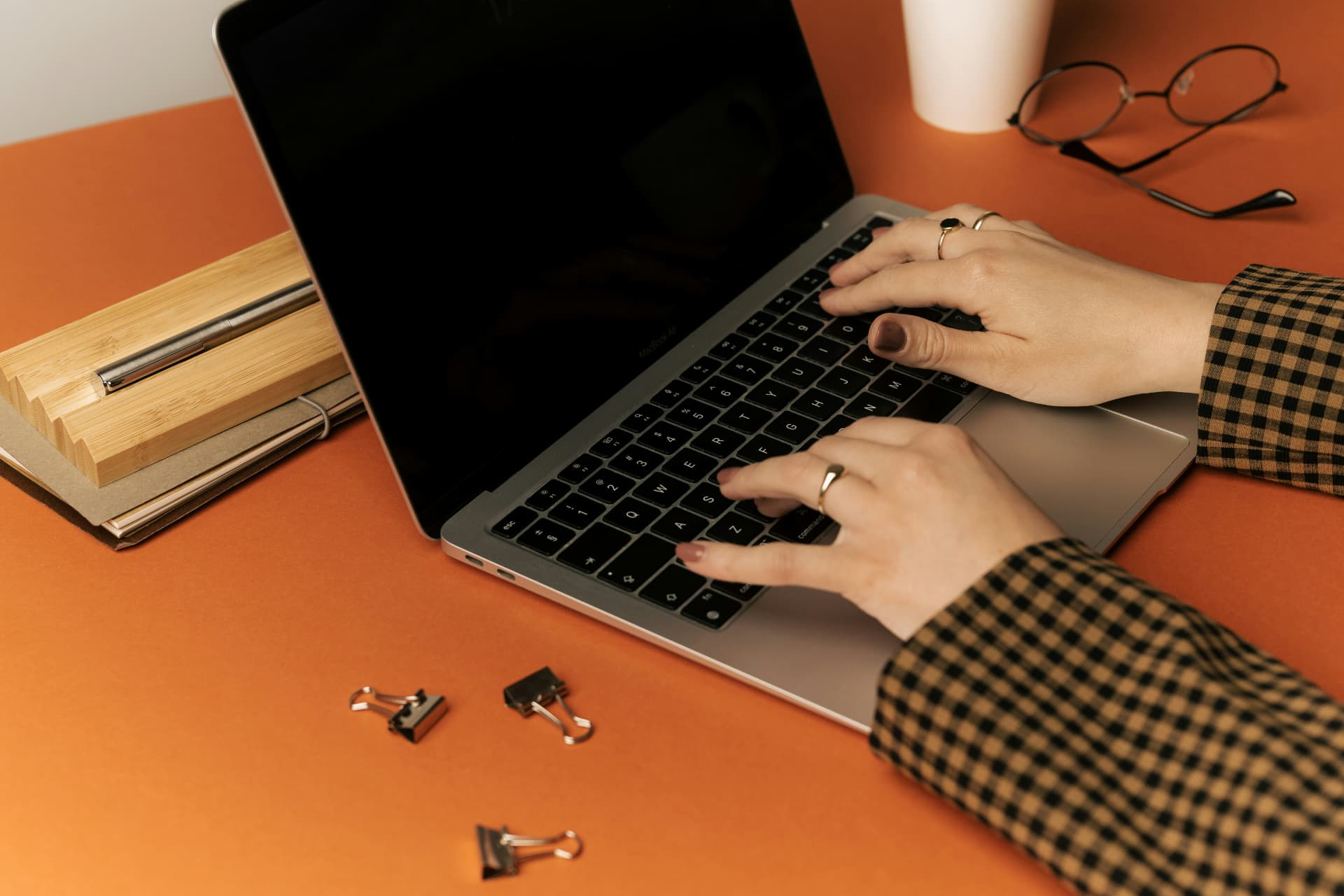 Hands at a laptop on a warm desk, representing thoughtful work in a digital age